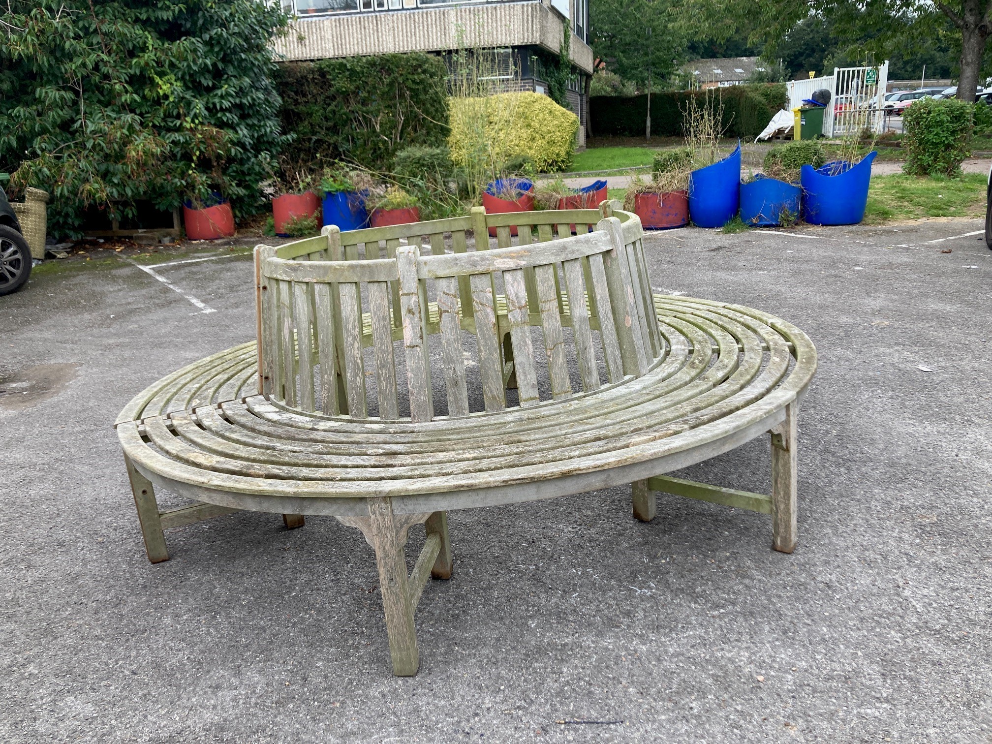 A weathered teak two section garden tree seat, diameter approx. 210cm, height 87cm, aperture approx. 116cm